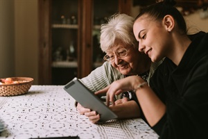 Granddaughter helping grandmother with digital device