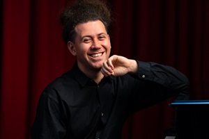 Pianist Liam Wooding sits at a piano
